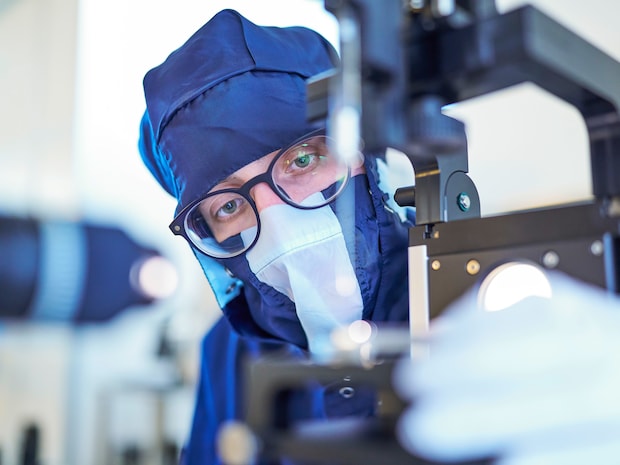 Employees wearing glasses and dark blue cleanroom clothing